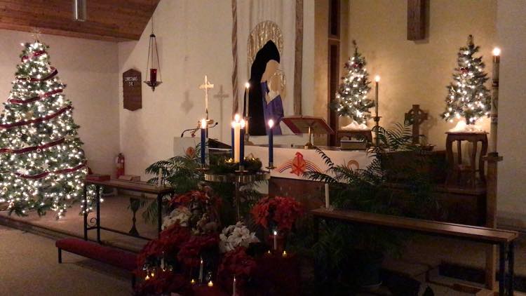 Display of Christmas decorations at the alter with lit candles.