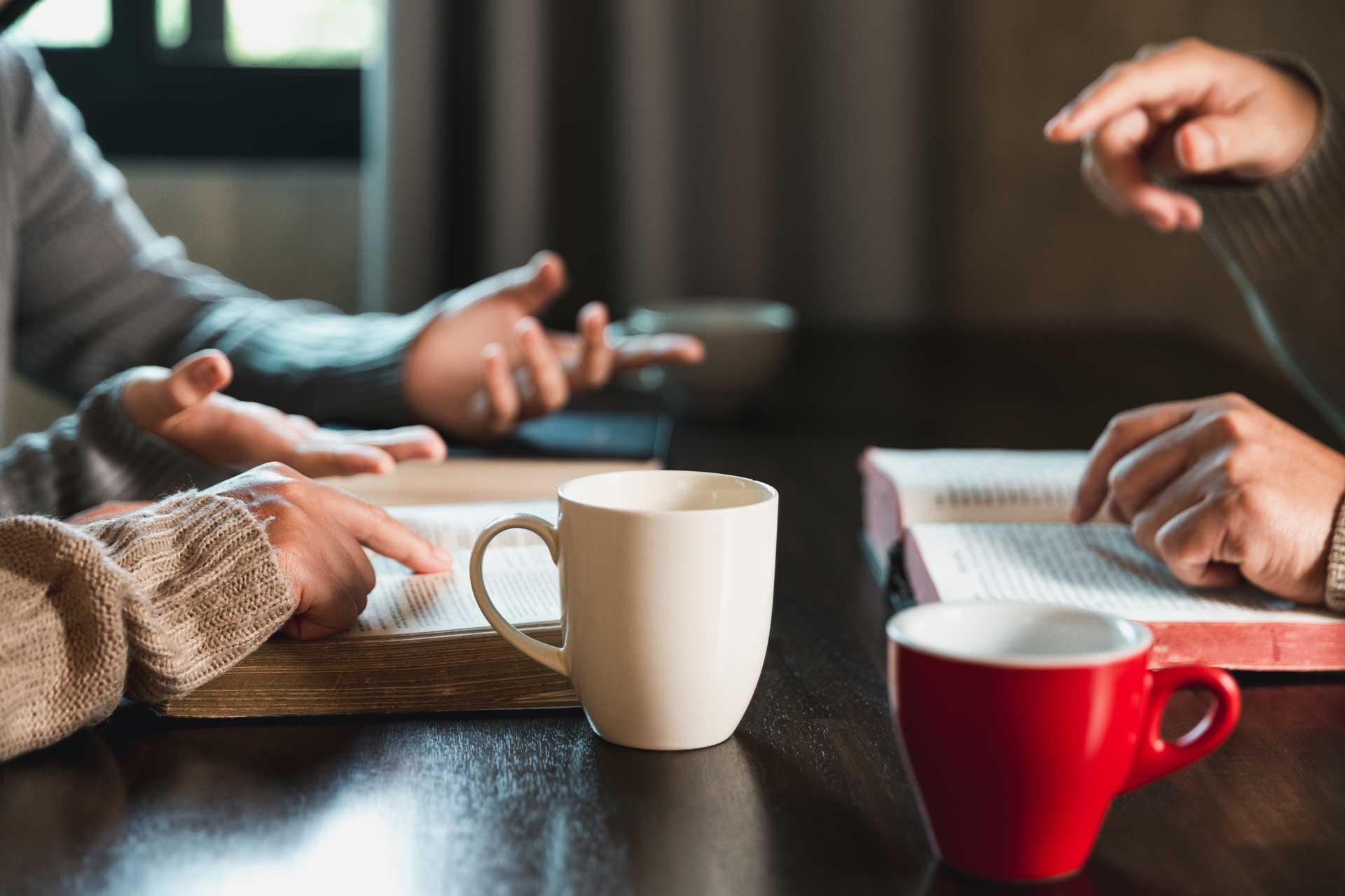 Adults drinking coffee and discussing bible scripture.